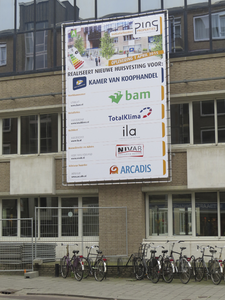 872102 Afbeelding van het grote spandoek over de nieuwe huisvesting van de Kamer van Koophandel op de gevel van het ...